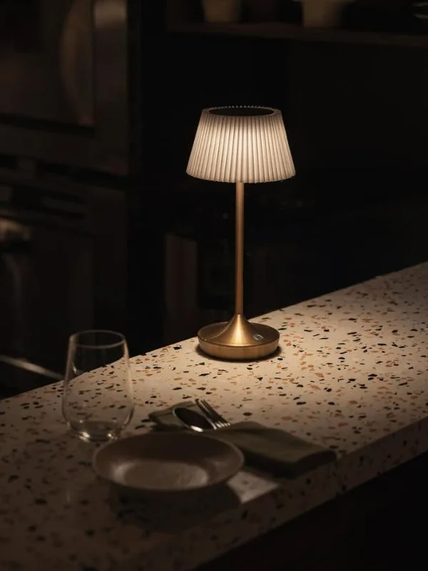 Cận cảnh mặt bàn terrazzo điểm đèn để bàn mạ vàng và bộ đồ ăn – chi tiết tạo nên không khí ấm áp