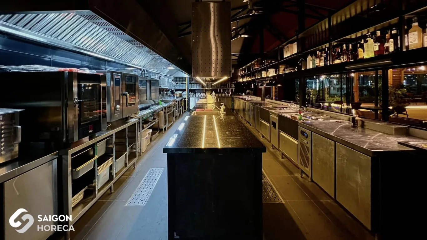 Toàn cảnh khu bếp công nghiệp inox và quầy bar đã hoàn thiện của Sol Kitchen & Bar Quận 7: lò nướng combi, tủ mát, chụp hút khói và đảo bếp mặt đá granite