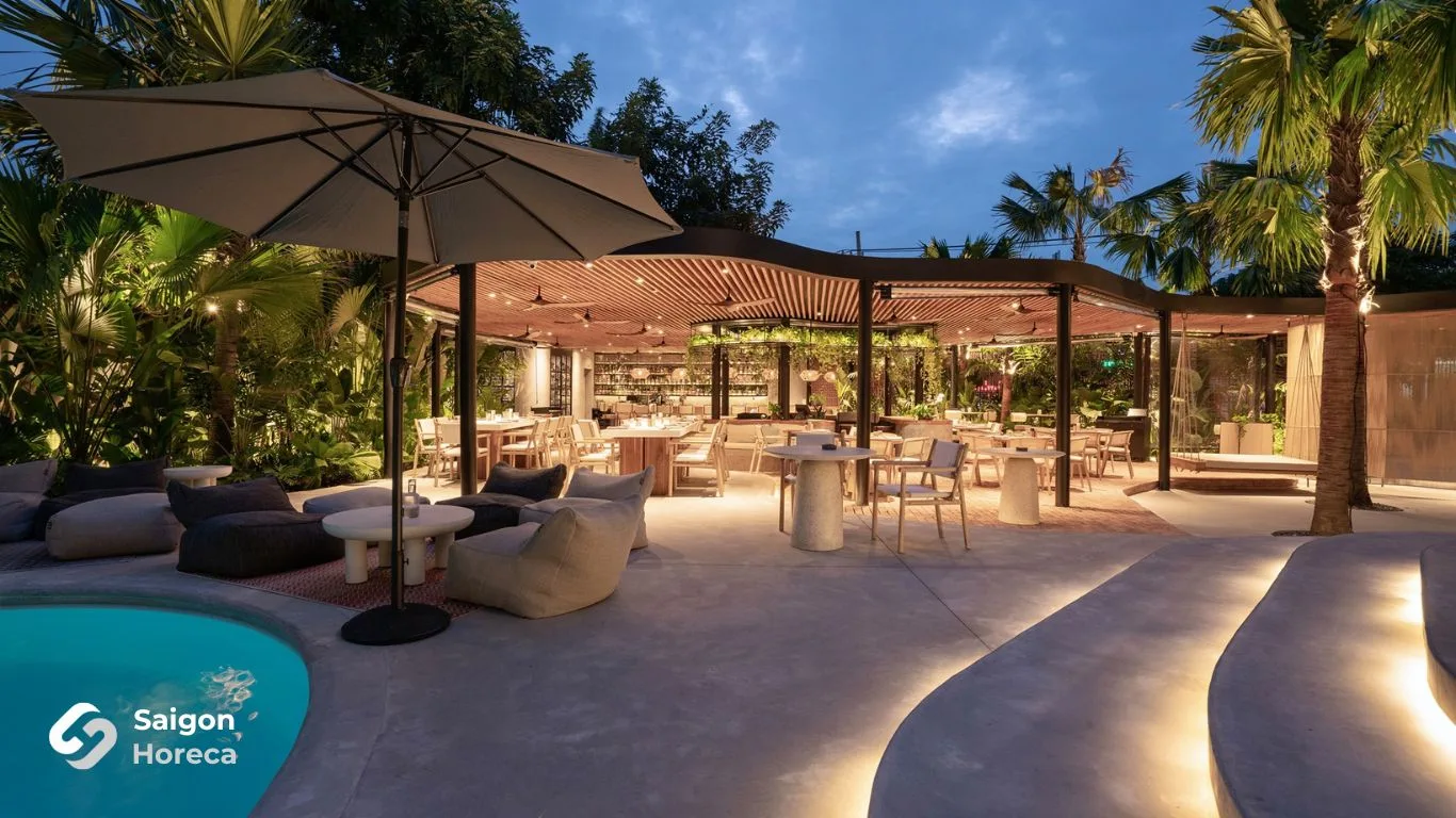 Khu lounge ngoài trời The Brix với ô dù và sofa bên hồ bơi lúc chạng vạng