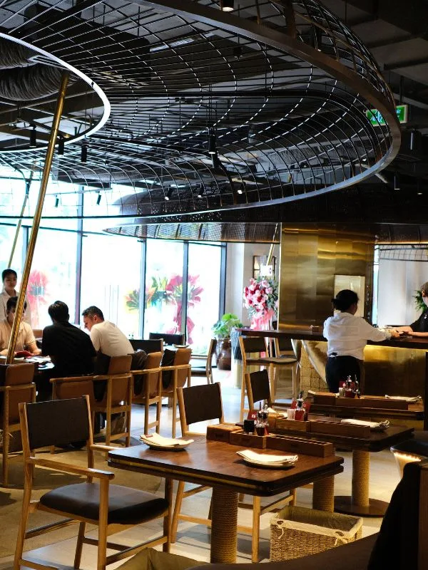 Bàn ghế gỗ trầm và quầy bar trung tâm tại The Cheezy Time