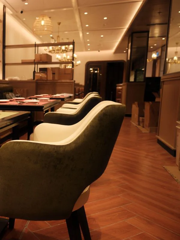 Details of premium green velvet-upholstered chairs and wooden tables at The Royal.