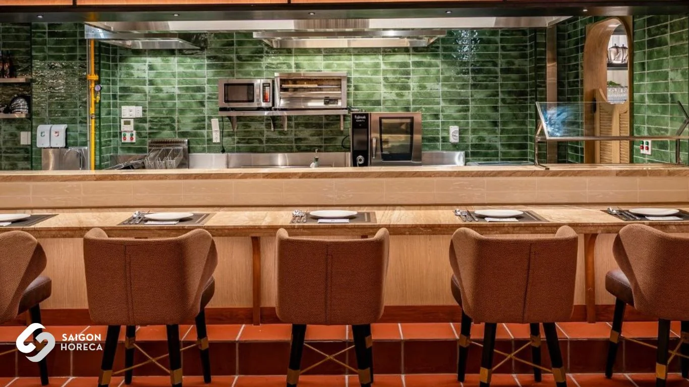 Signature moss-green tiled open kitchen equipped with Fujimak oven and cozy brown tweed bar stools at The Royal All Day Dining